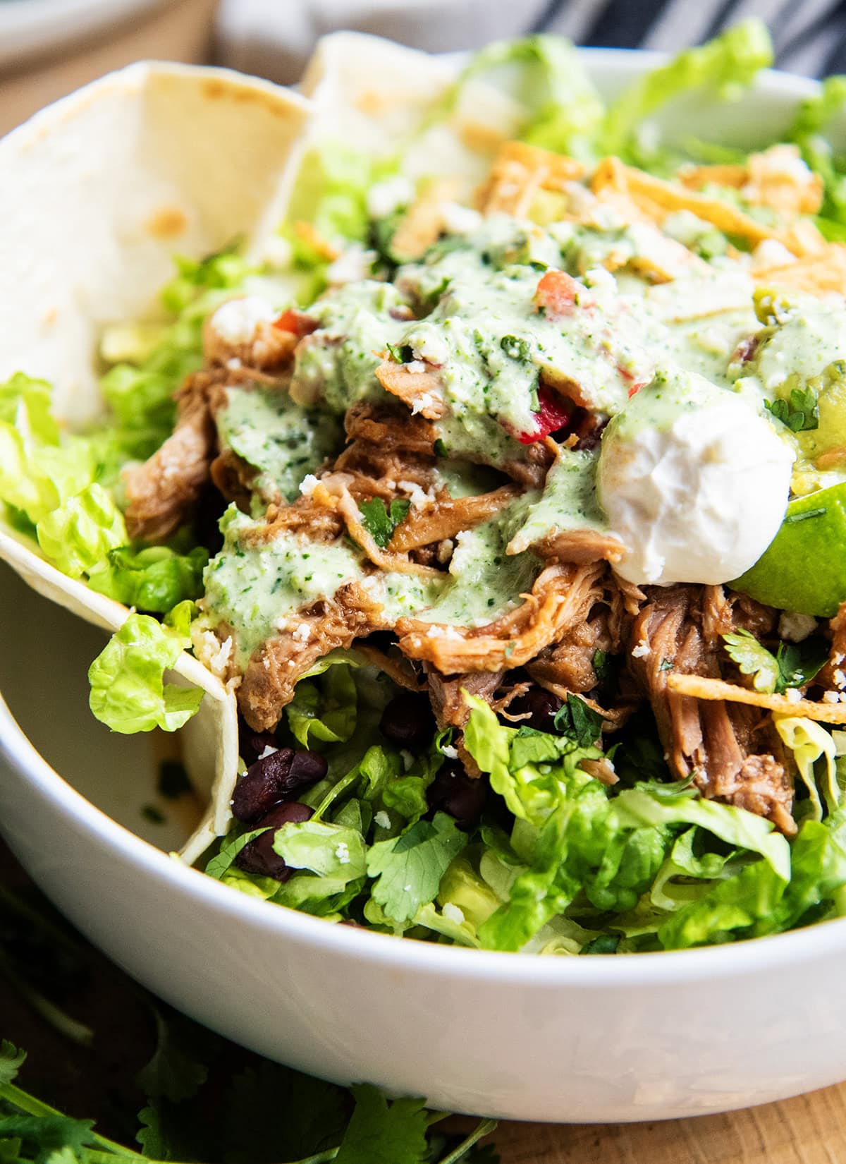 A close up of a copy cat of costa vida sweet pork salad with tomatillo ranch on top of a pile of pork with other taco toppings.