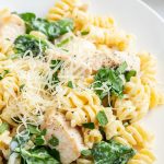 A plateful of creamy lemon chicken pasta with spinach, topped with freshly grated parmesan cheese.