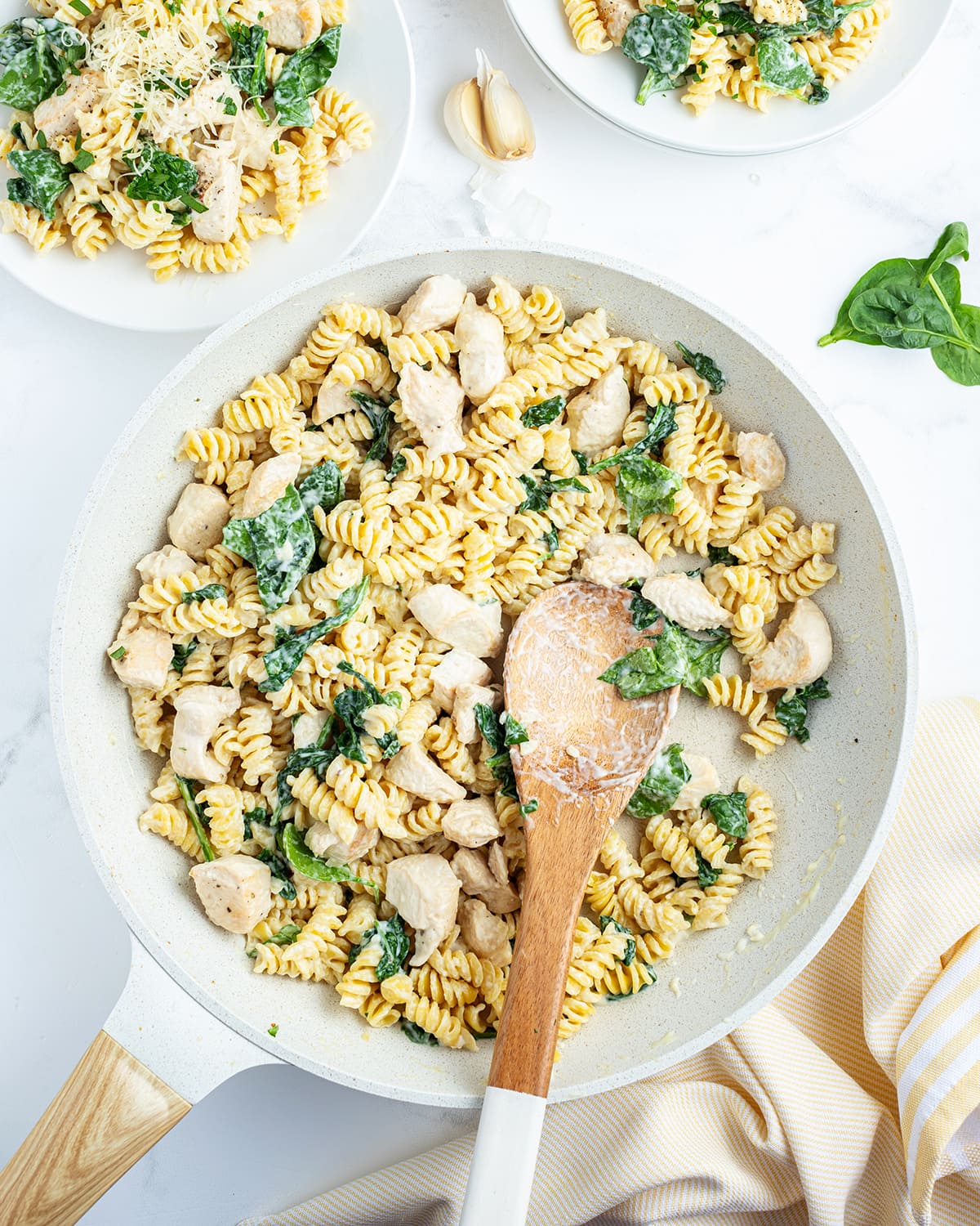 A pan of lemon chicken pasta with big pieces of chicken, and spinach in it.