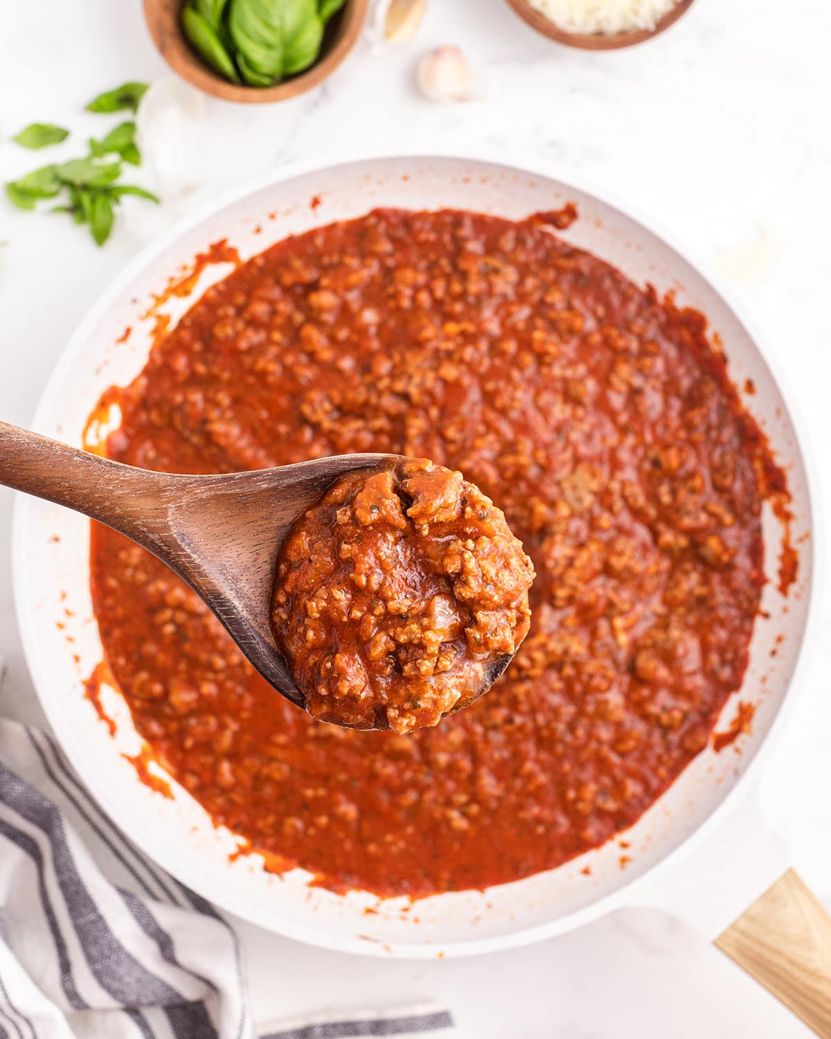 A pan spaghetti sauce with a wooden spoon holding the sauce above it.