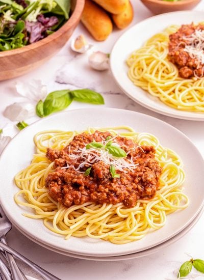 A plate of spaghetti topped with a meat sauce and fresh basil.