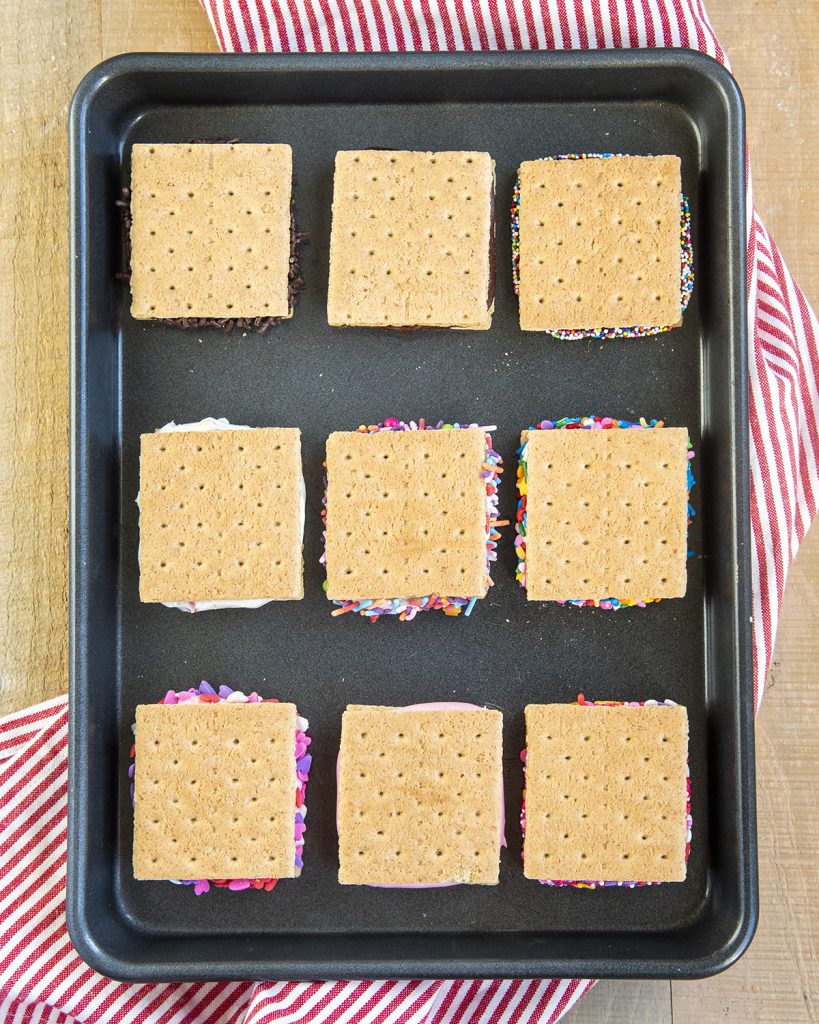 An overhead photo of 9 graham cracker cookie sandwiches on a small cookie sheet.