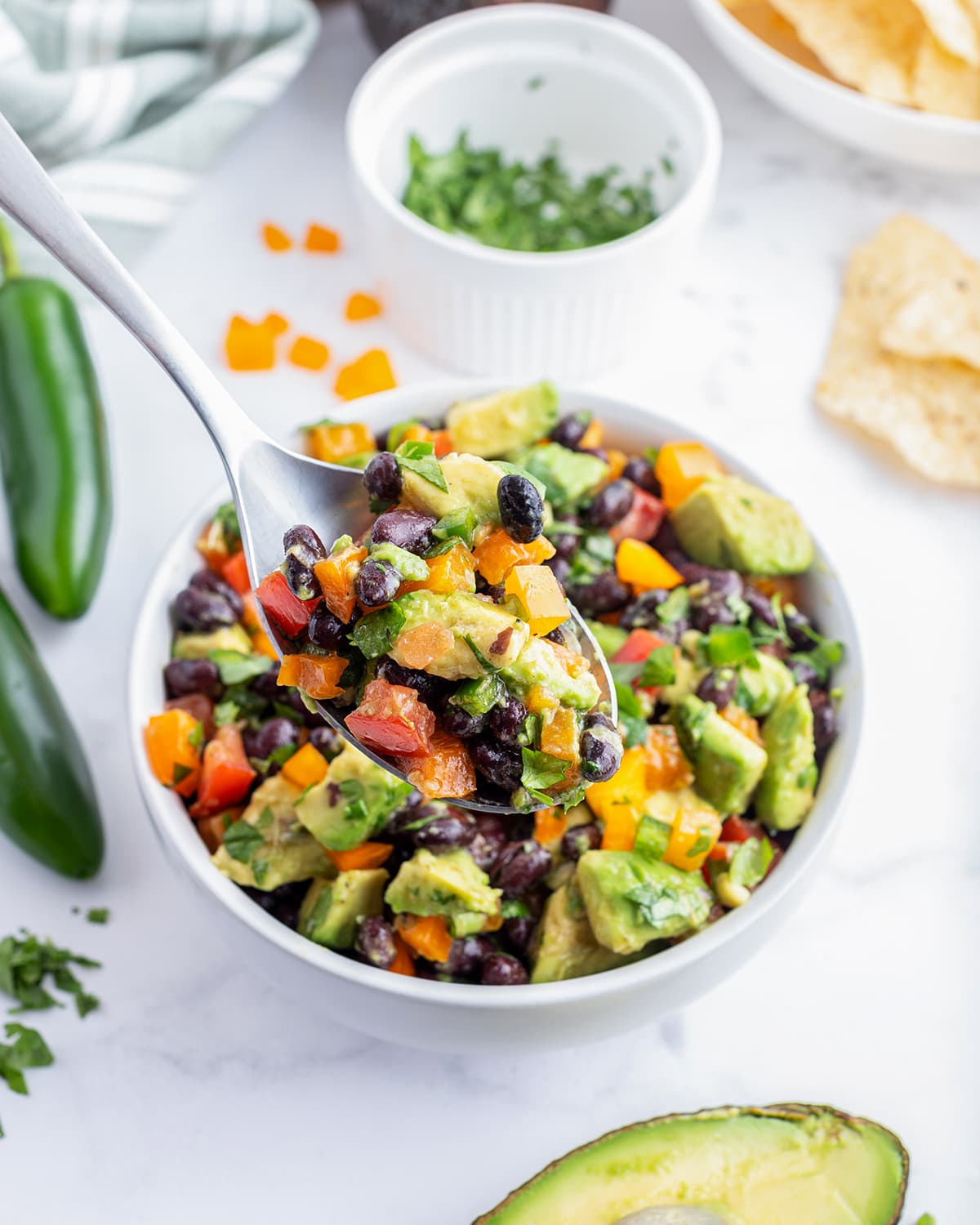 A spoonful of avocado black bean salad above a bowl of it. 