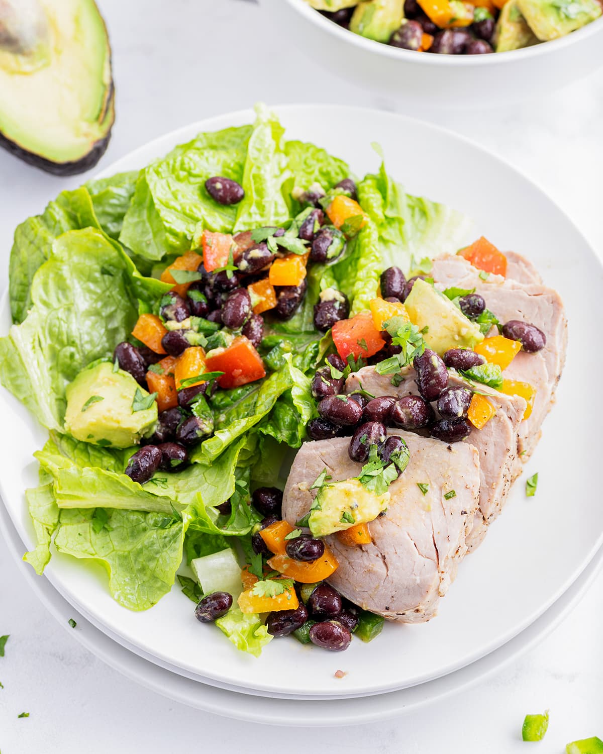 A plate of lettuce and pork topped with black bean salsa.