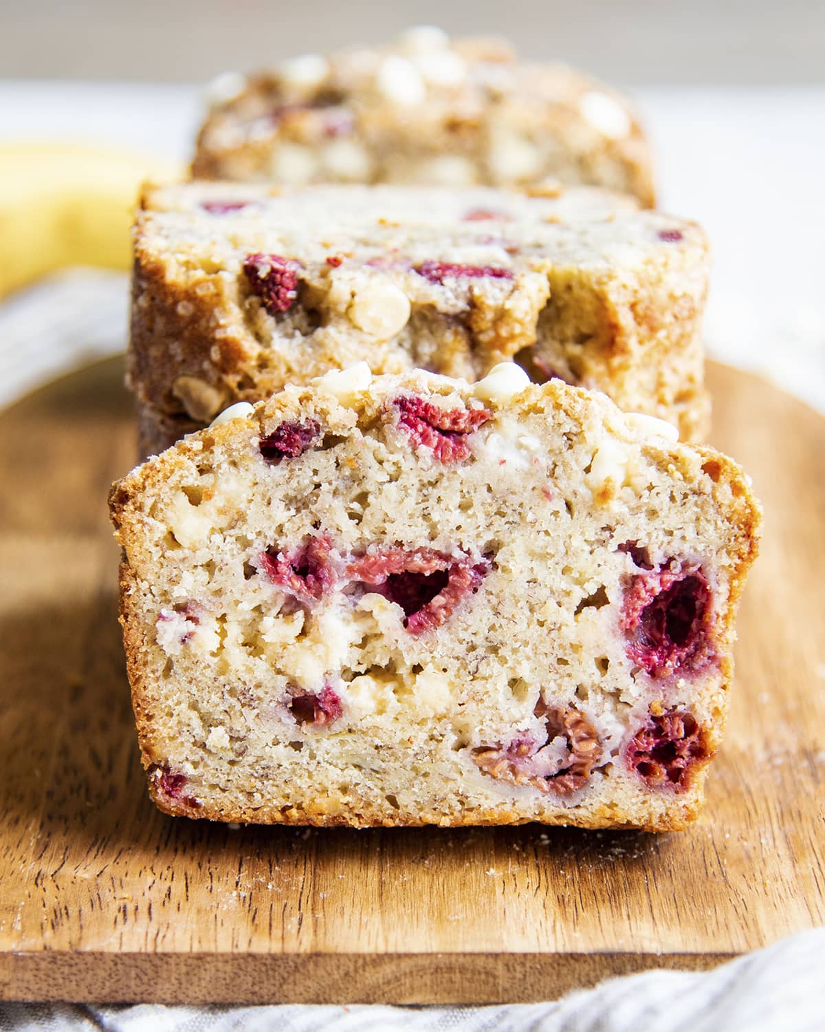 A slice of banana bread with raspberries and white chocolate chips.