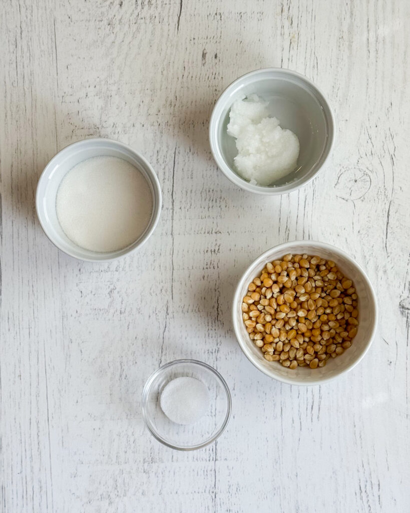 Four small bowls of the ingredients needed to make Kettle Corn at home. 