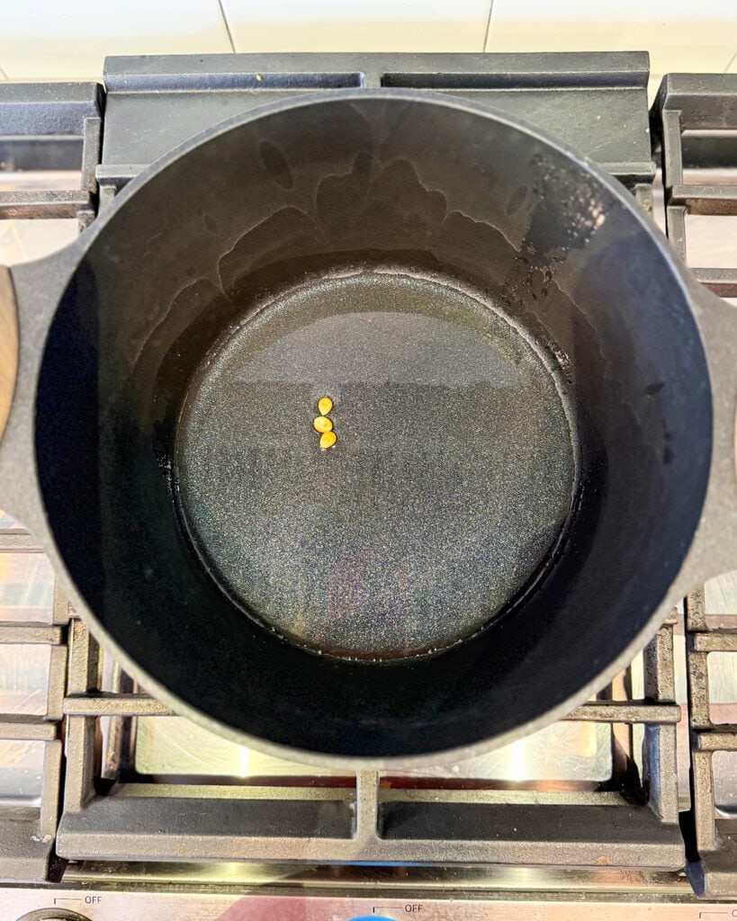 A pot of oil with three popcorn kernels.