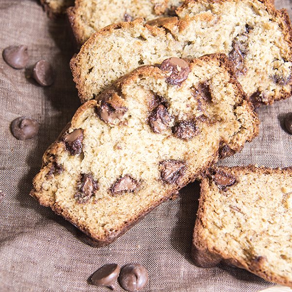 Close up view of chocolate chip banana bread on a brown backdrop.