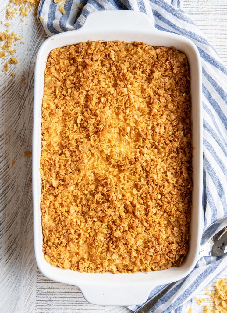 An overhead photo of a baking pan full of funeral potatoes topped with cornflakes.