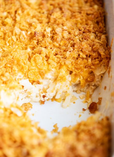 A pan of cheesy funeral potatoes topped with crushed cornflake cereal.