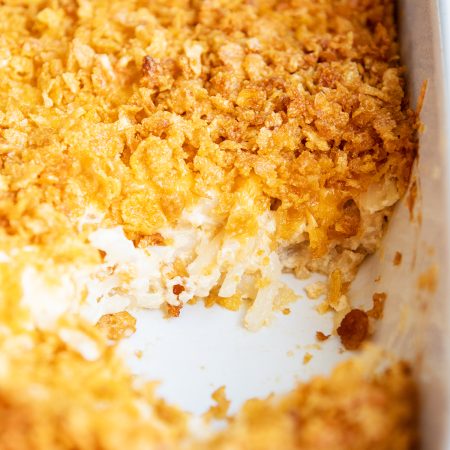 A pan of cheesy funeral potatoes topped with crushed cornflake cereal.