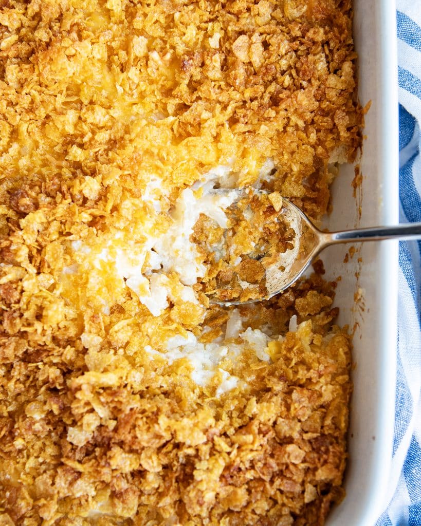A baking pan of funeral potatoes with a spoon in the dish.
