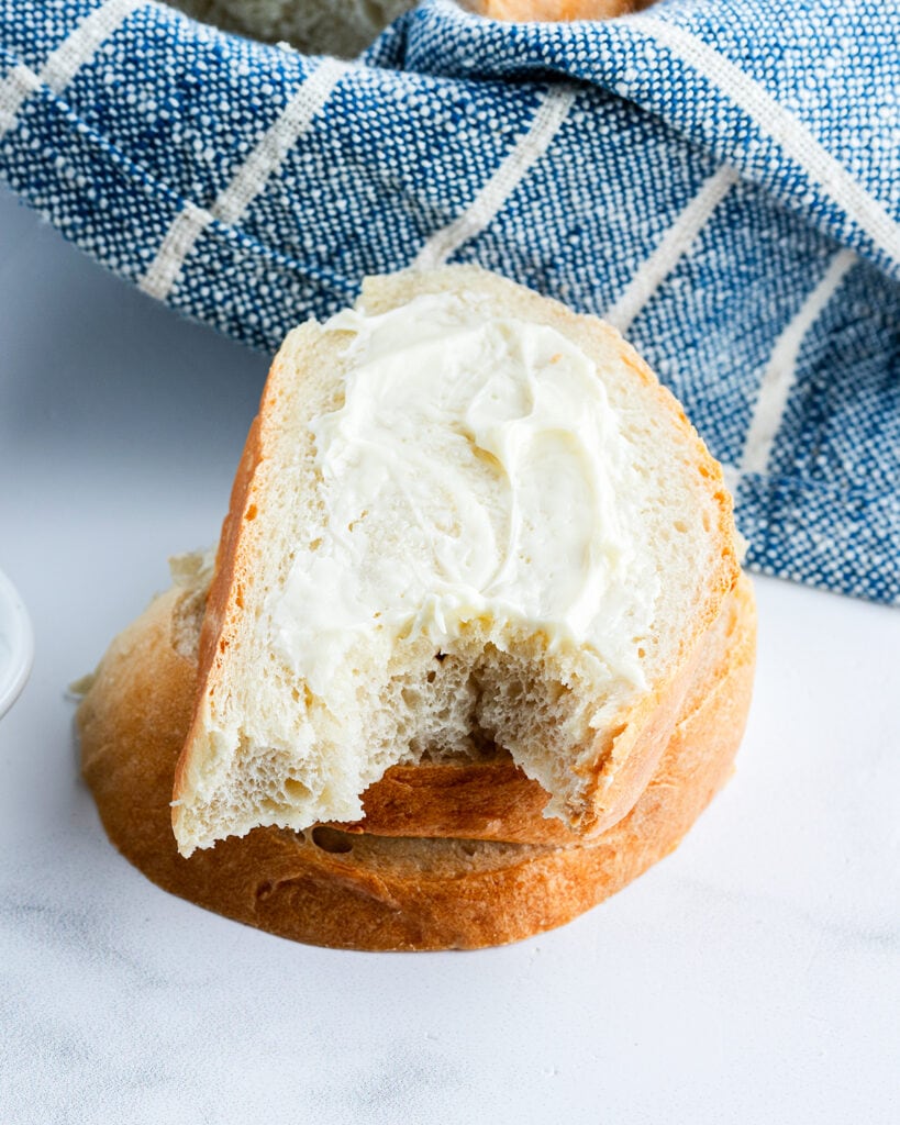 A slice of French bread slathered with butter, and with a bite out of it.