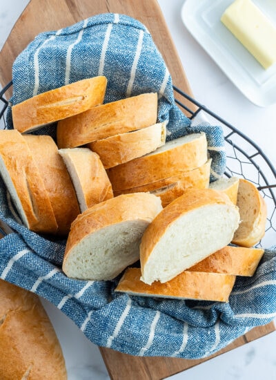 A basket lined with a blue towel, with slices of French bread.