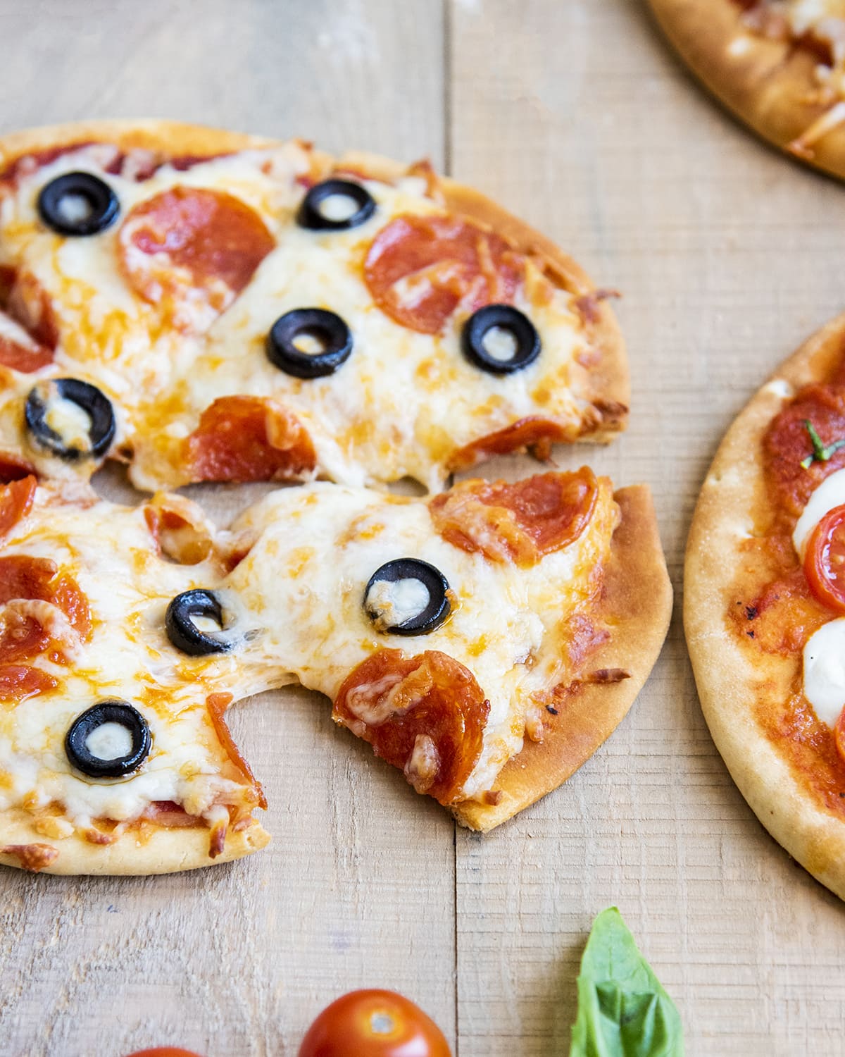 A pepperoni and olive pita pizza that is cut into slices.