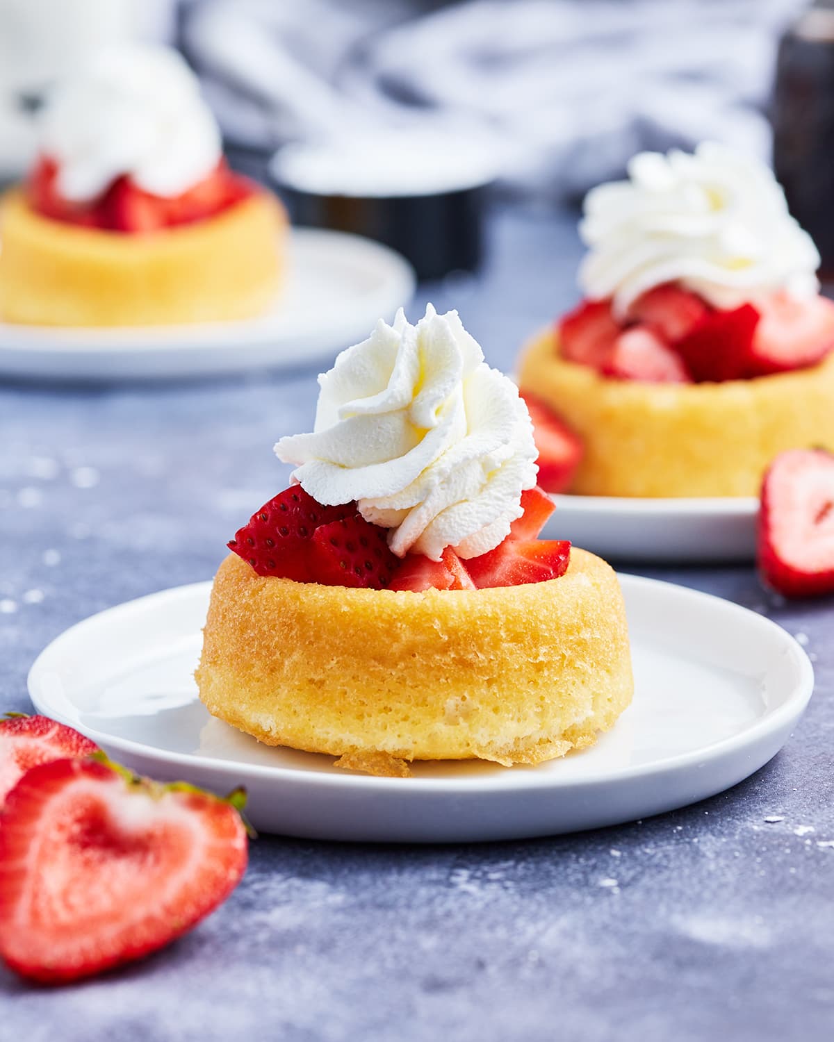 A mini pound cake topped with strawberries and whipped cream on a plate.