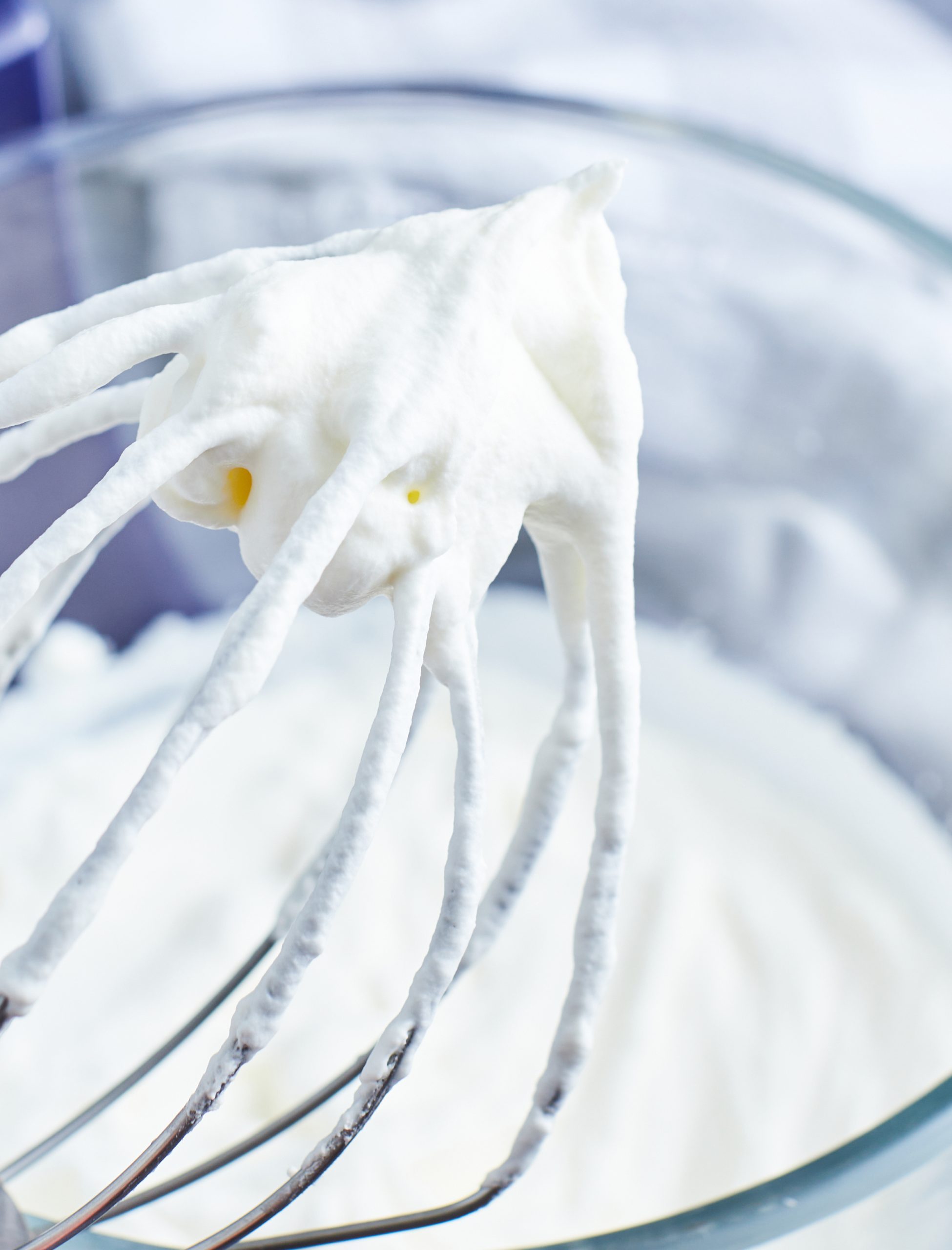 A whisk with stiff whipped cream on it.
