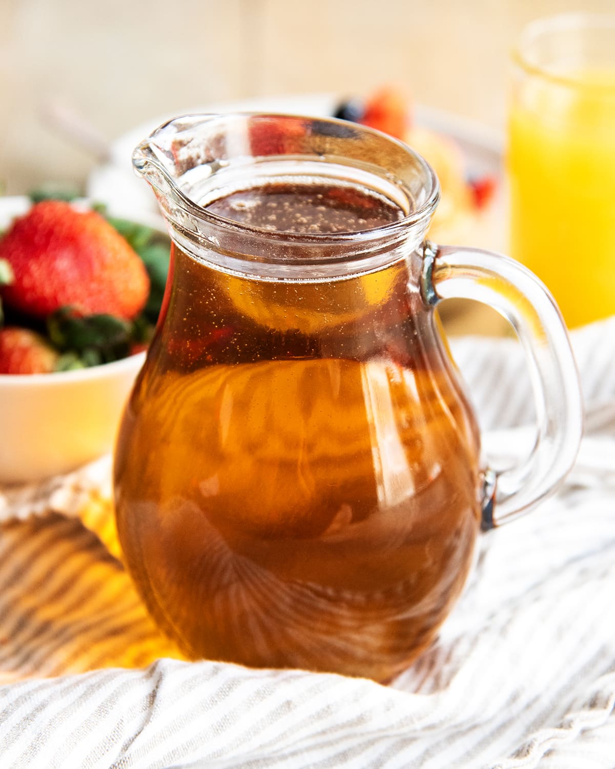 A glass pitcher of maple flavored syrup.
