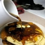 Syrup being poured over pancakes.