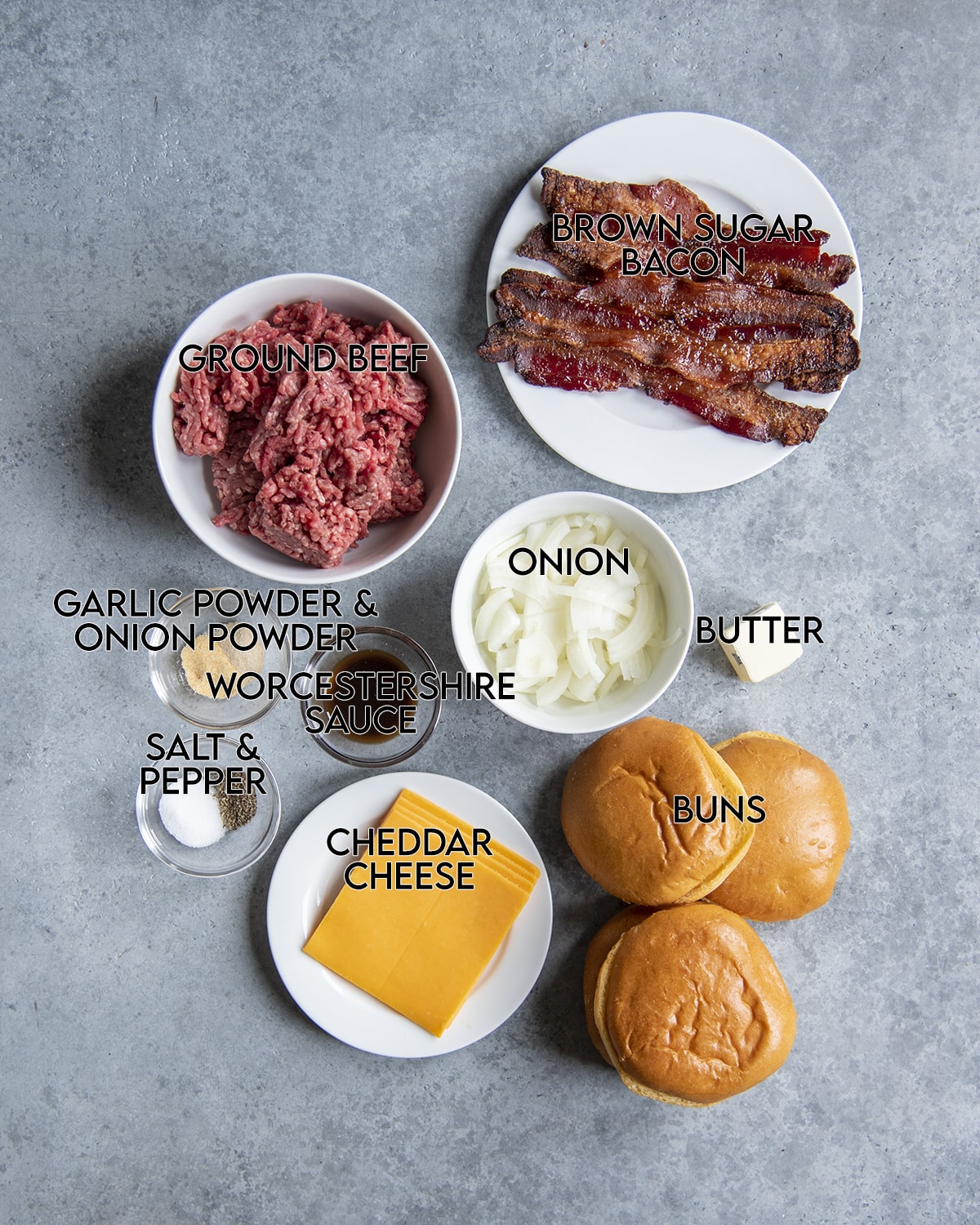 The ingredients needed to make brown sugar bacon burgers, they are each labeled; ground beef, brown sugar bacon, onions, garlic powder and onion powder, salt and pepper, worcestershire sauce, cheese, buns, butter.