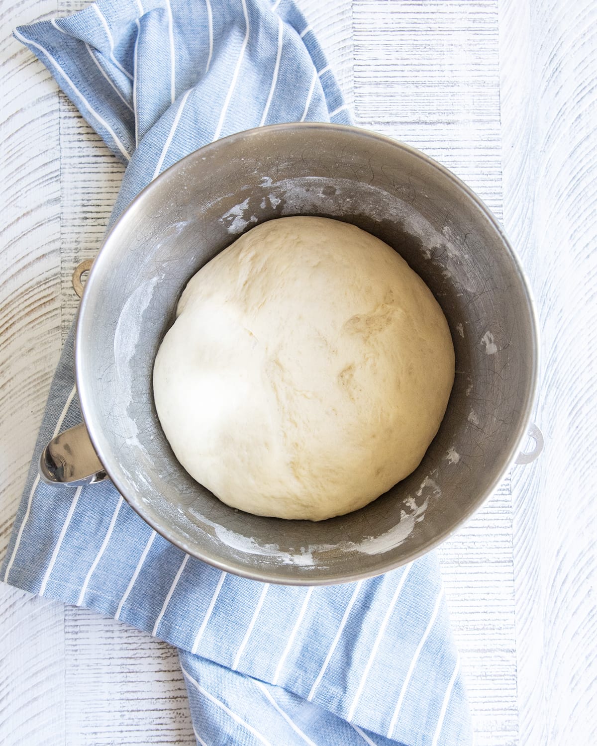 A ball of dough in a metal bowl.