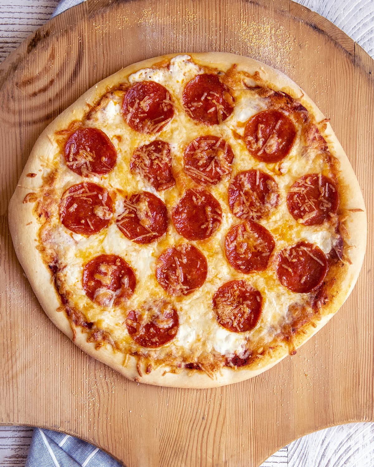 Pepperoni pizza on a pizza peel, with golden melted cheese.