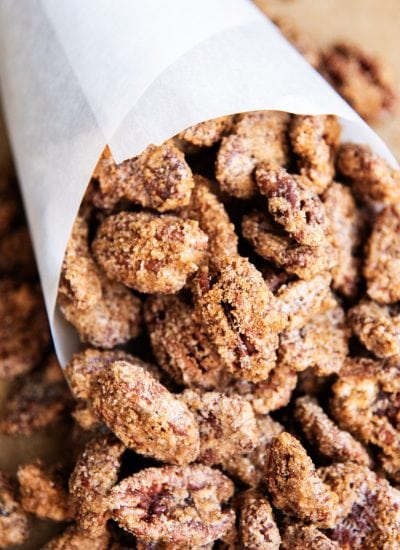 Cinnamon Sugar Pecans wrapped in a cone of paper, on a table.