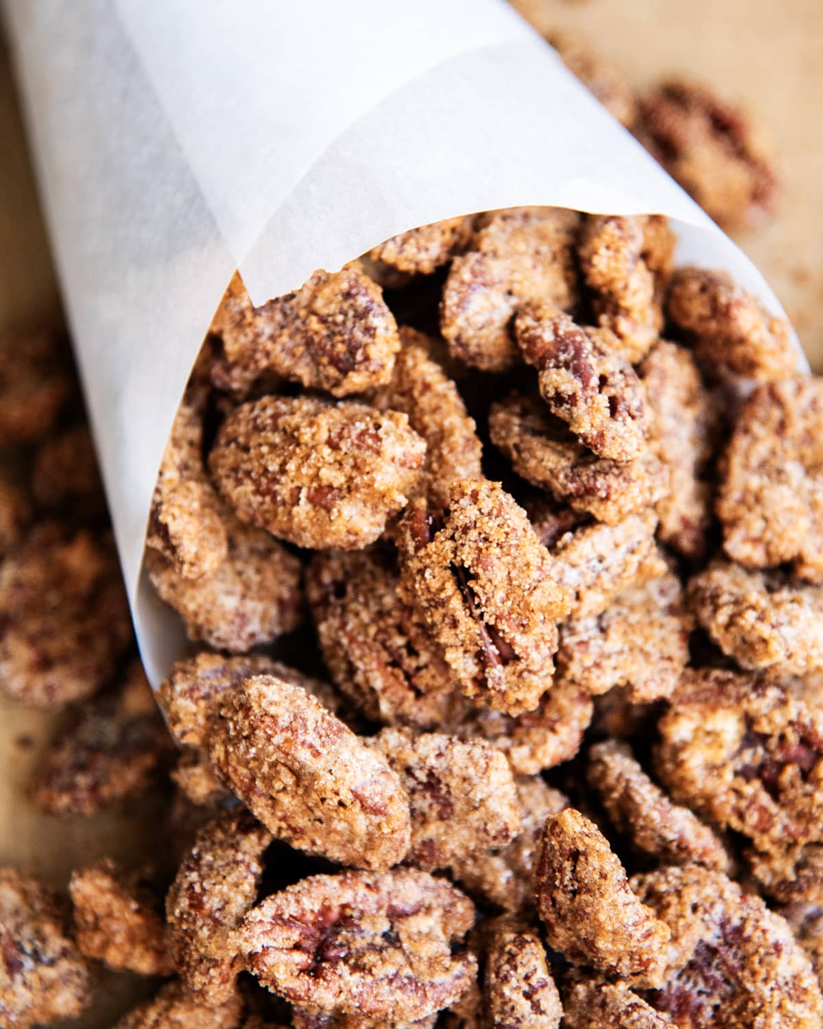 Cinnamon Sugar Pecans wrapped in a cone of paper, on a table.