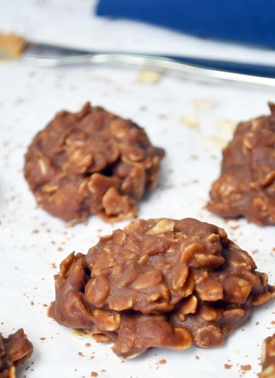 a picture of 3 no bake cookies on parchment paper with cocoa powder sprinkled around