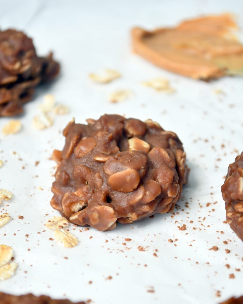 a picture of 1 no bake cookie in the middle of parchment paper with cocoa powder sprinkled around