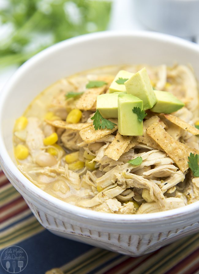 A bowl of white chicken chili topped with tortilla strips and diced avocado. 