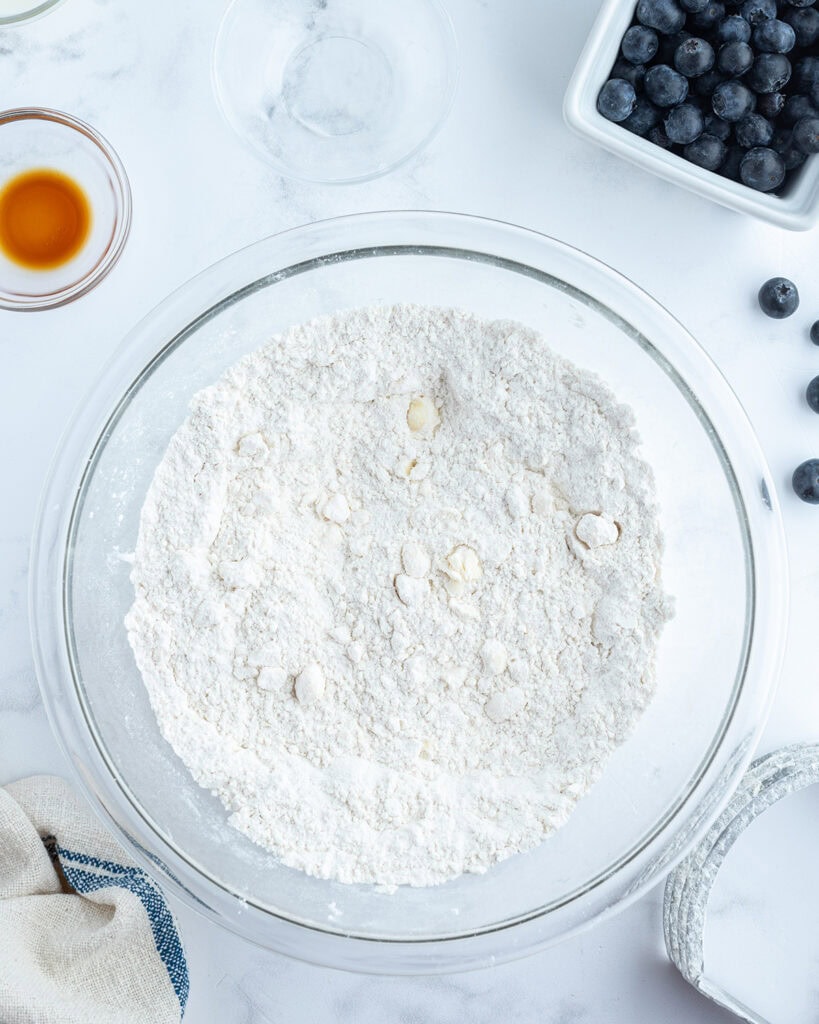 A bowl of butter cut into flour to make a crumbly, sandy texture.