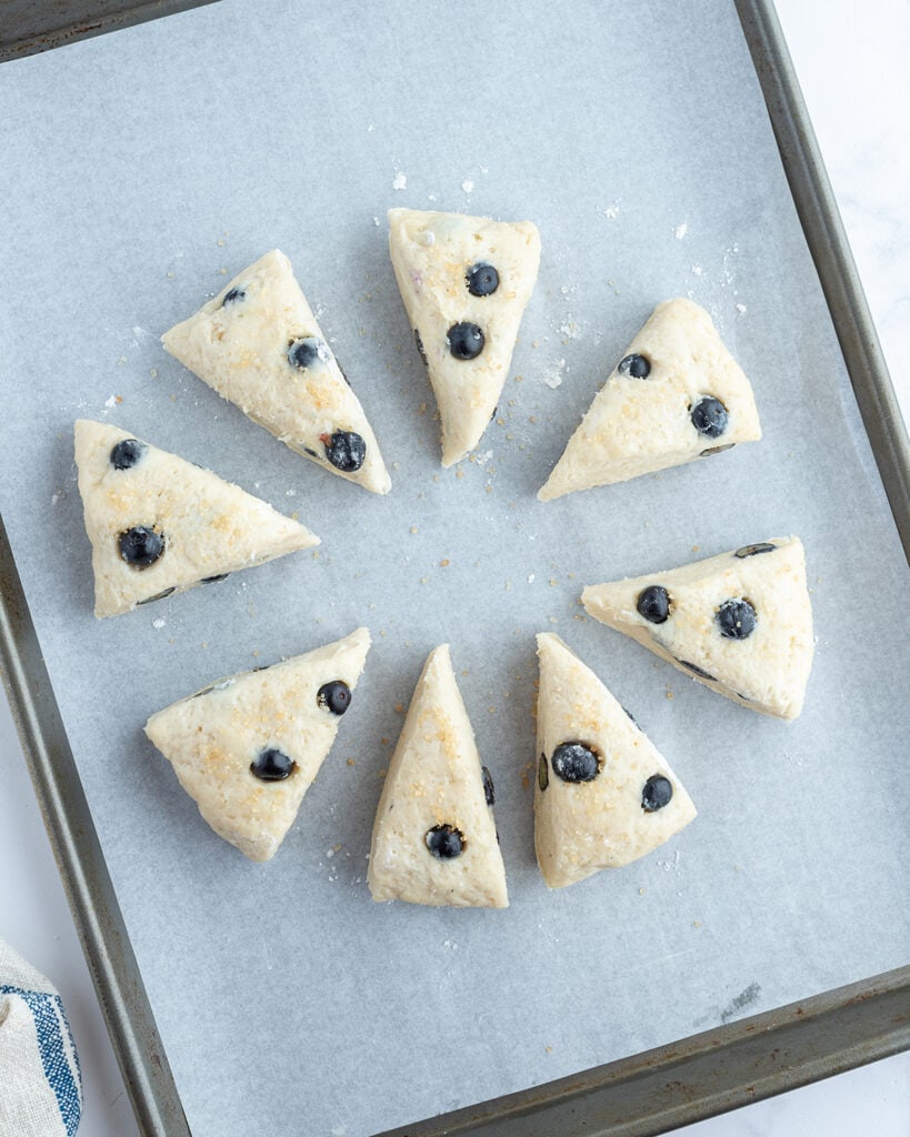 Uncooked triangle scones on a baking sheet.