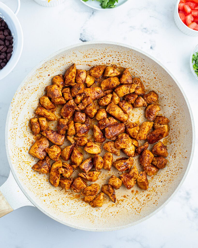 A saute pan full of cooked chicken.