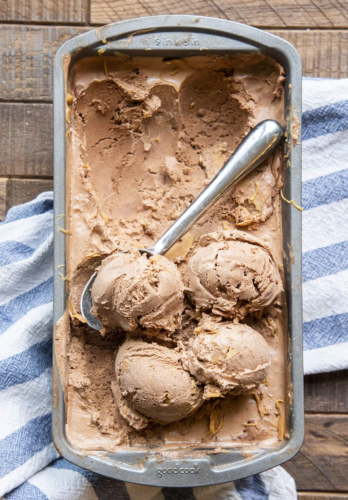 An overhead shot of chocolate ice cream in a bread pan, with 4 round scoops on one end.