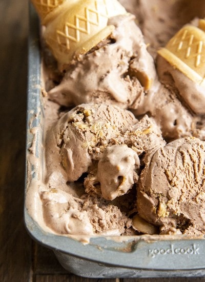 A close up of scoops of chocolate peanut butter ice cream in a metal pan, with an upside down cone on top.