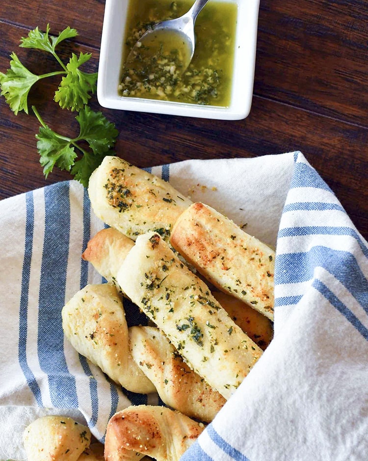 Garlic bread sticks peaking out of a towel that is wrapped around them on top and bottom.