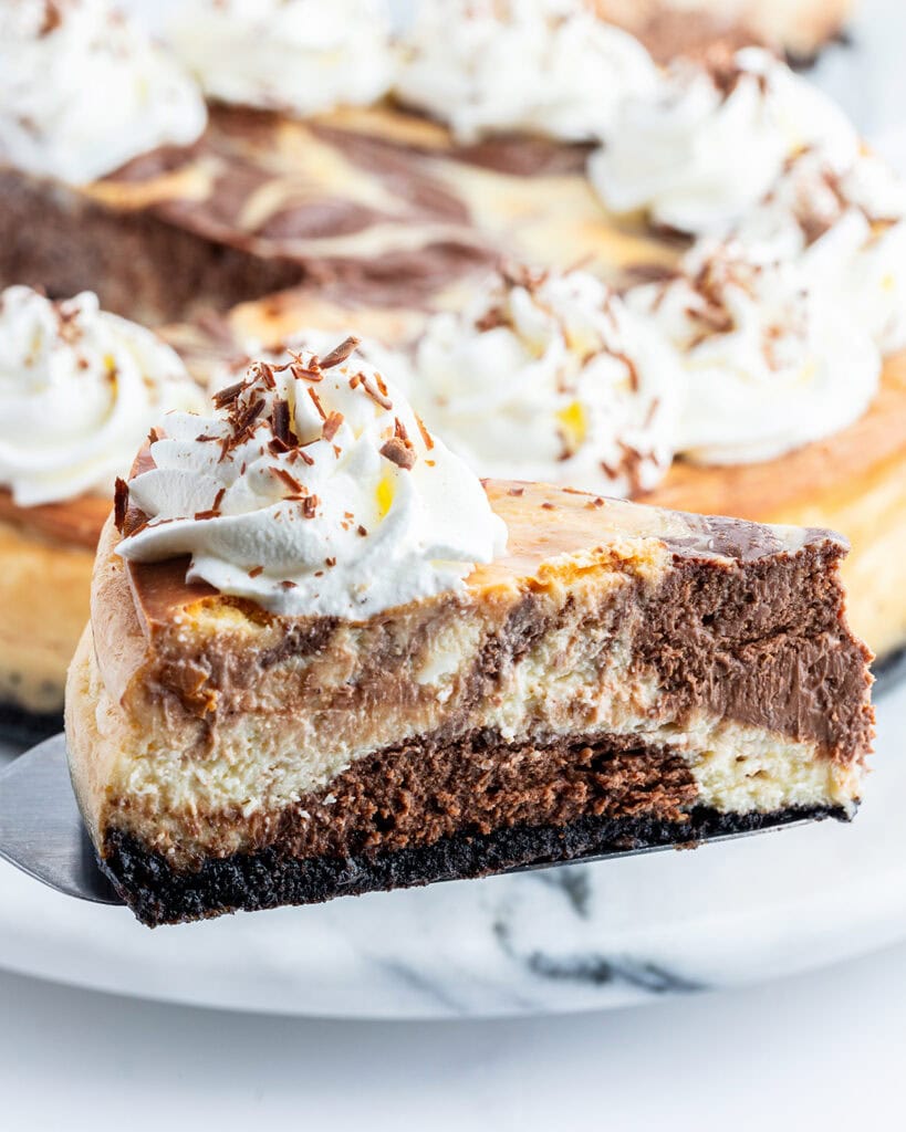 A slice of chocolate marbled cheesecake on a spatula.