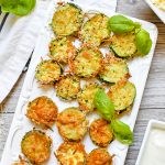 Top view of parmesan zucchini bites on a white plate.