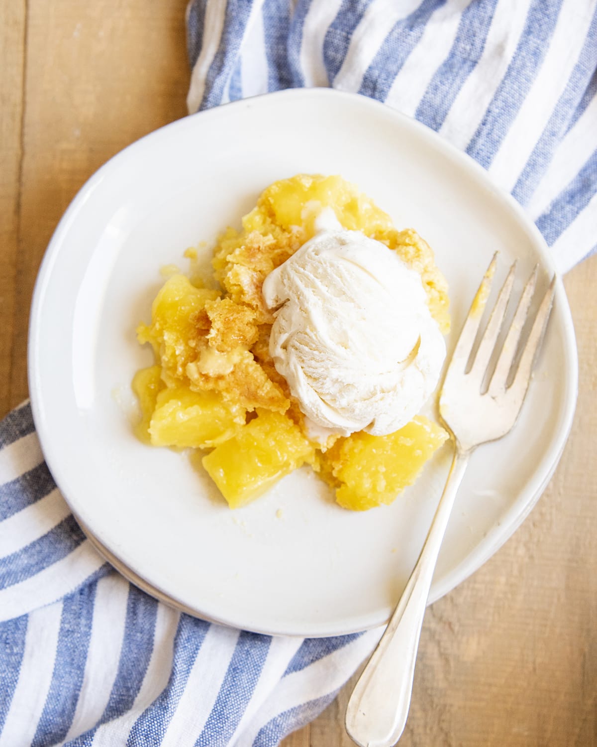 An overhead shot of a photo of pineapple cobbler topped with a scoop of ice cream.