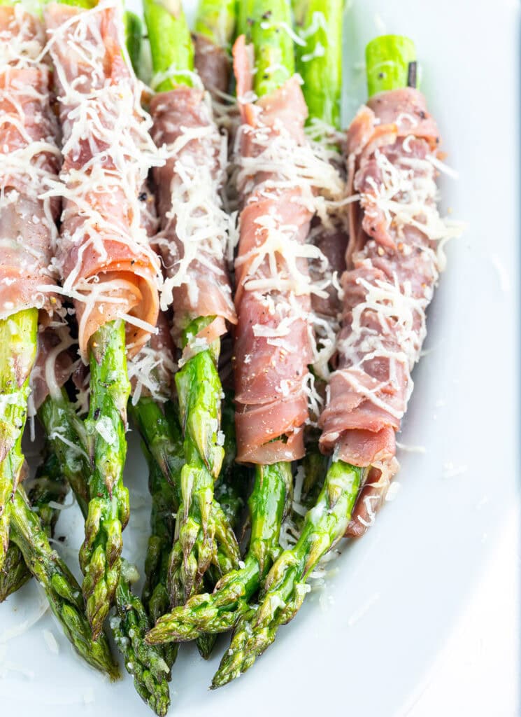 A close up of stalks of asparagus with prosciutto wrapped around them.