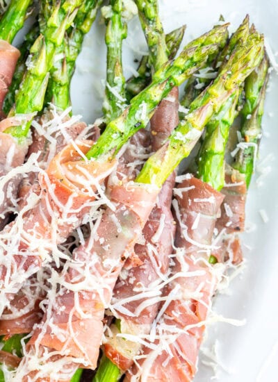 A close up of stalks of asparagus with prosciutto wrapped around them.
