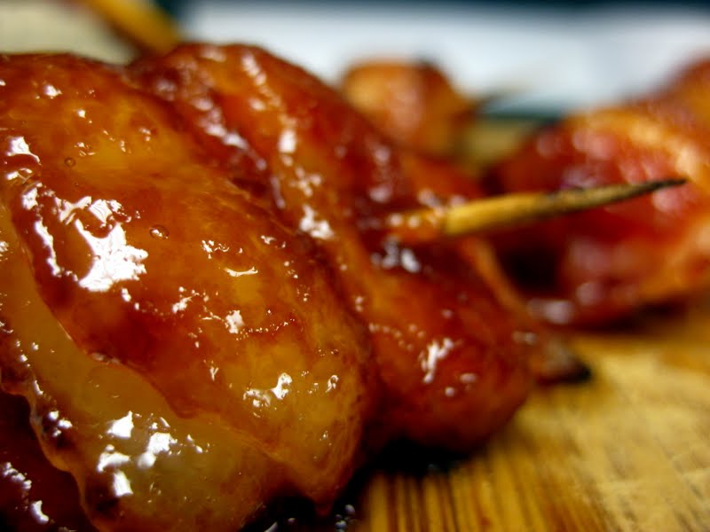 Close up view of sweet bacon wrapped pineapple on a wood board.
