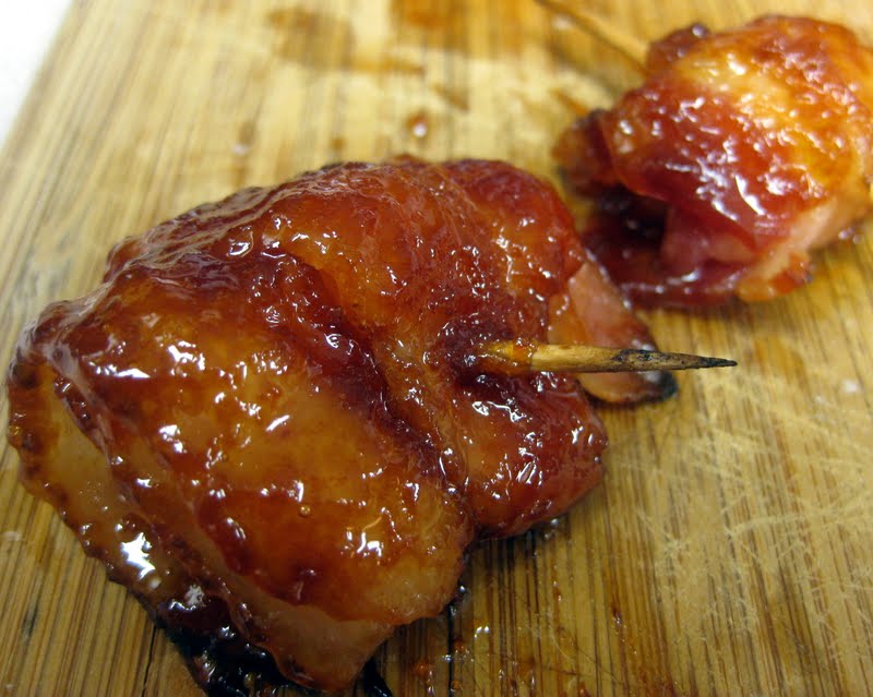 Angled view of sweet bacon wrapped pineapple on a wood board.