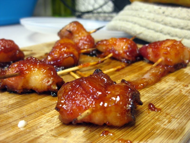 Front view of sweet bacon wrapped pineapple on a wood board.