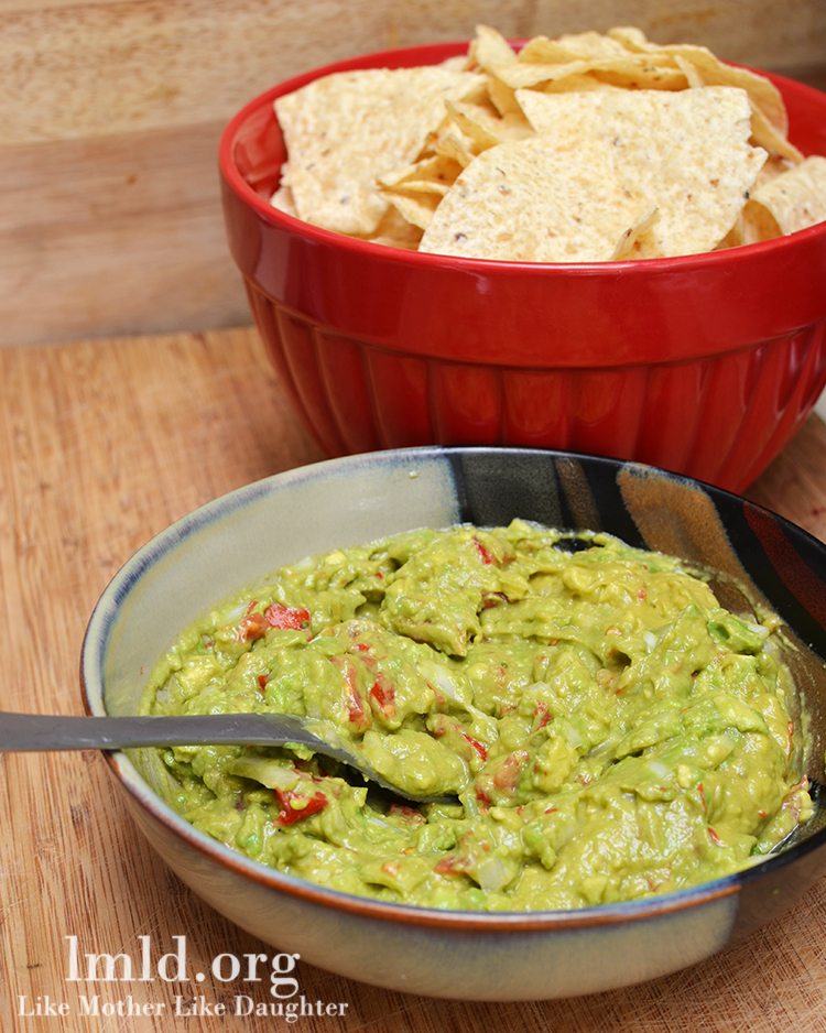 Angled view of fresh guacamole next to a bowl of chips.