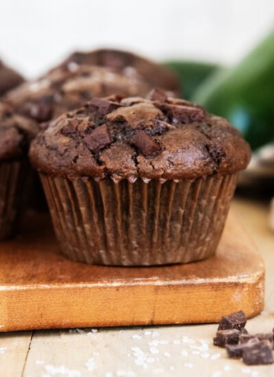 A zucchini and chocolate muffin on a wooden board.