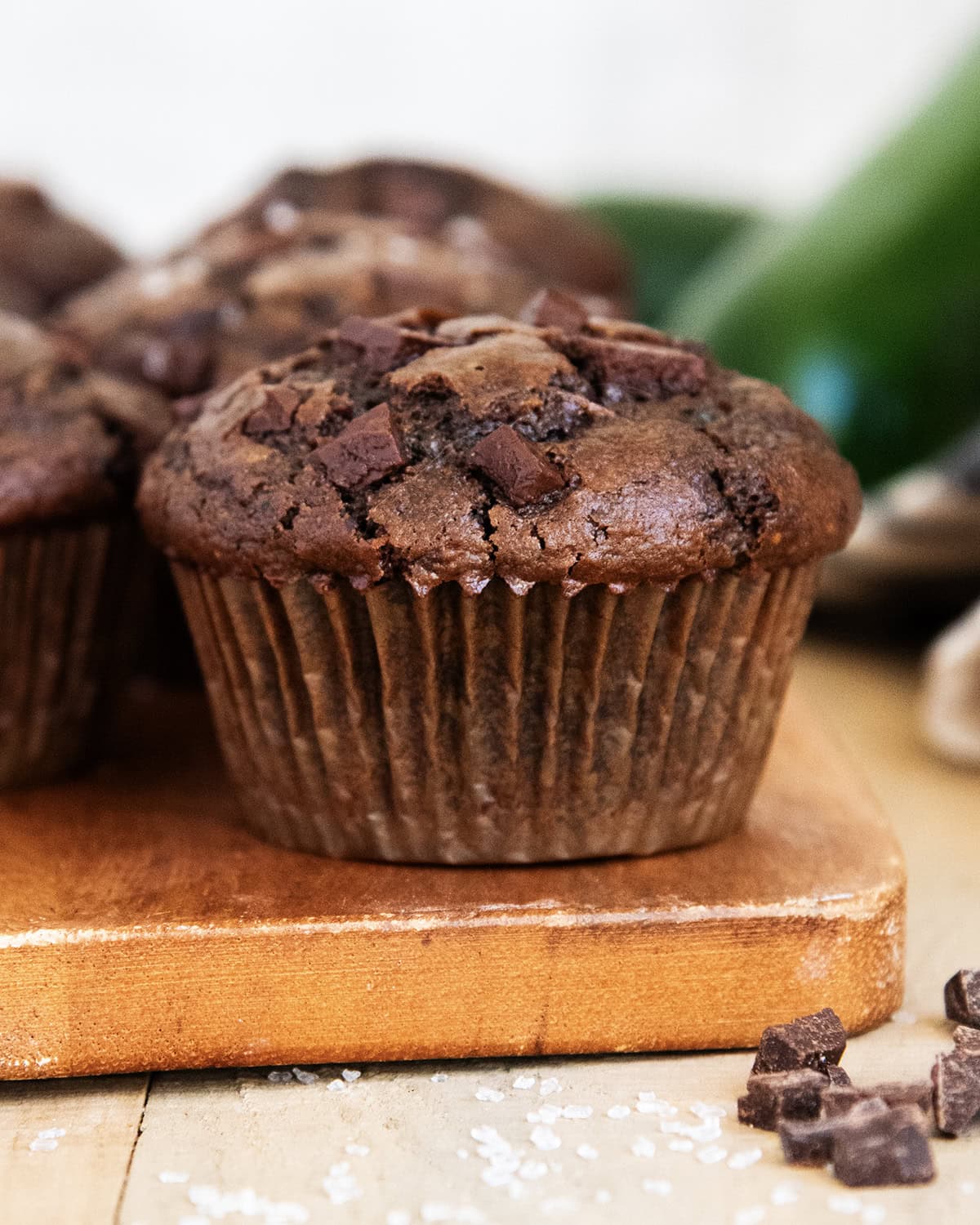 A zucchini and chocolate muffin on a wooden board.