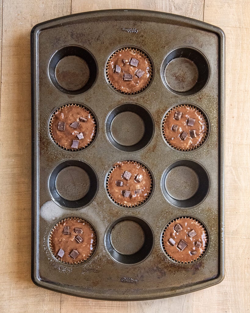 An above view of muffin batter in a pan, only every other slot is filled.