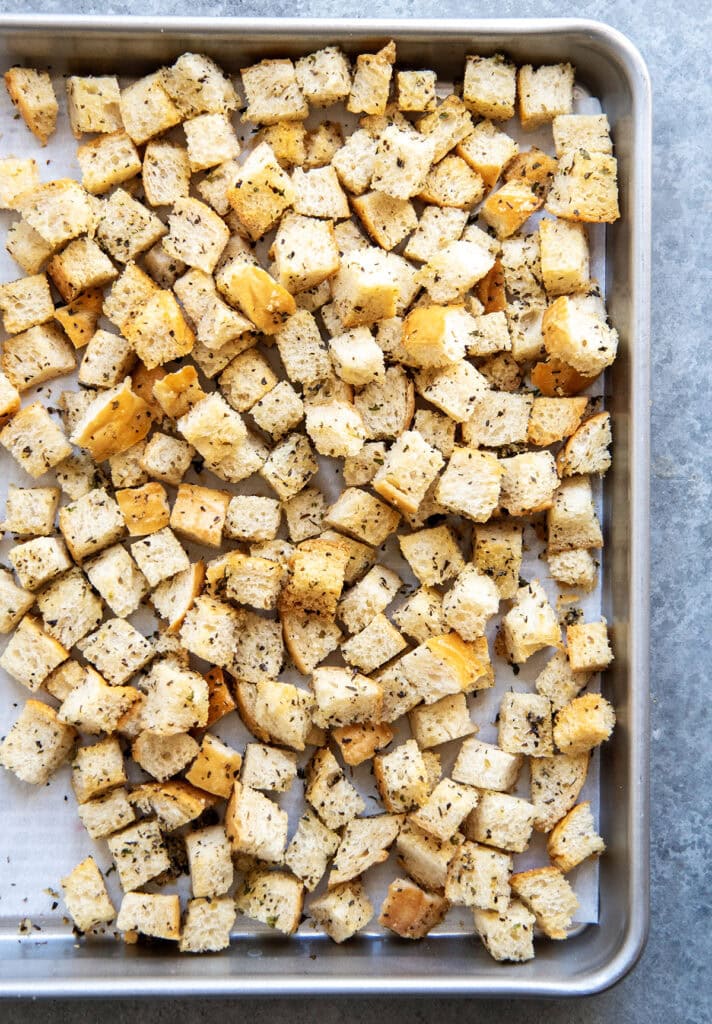 An overhead photo of croutons on a baking pan.